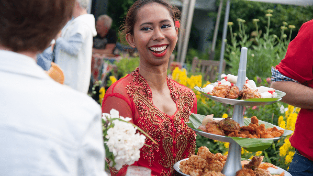 Gastvrouw met Indonesische gerechten bij een catering van Gembira